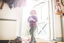 Menino de pé em uma porta das traseiras aberta — Fotografia de Stock