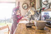 Girl washing dishes in kitchen sink — Stock Photo