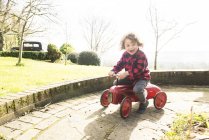 Ragazzo equitazione giocattolo trattore intorno giardino — Foto stock