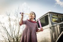 Girl blowing bubbles in front of car — Stock Photo