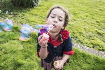 Дівчина дме бульбашки в саду — стокове фото
