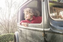 Niño sentado y mirando por la ventana del coche - foto de stock