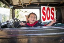 Menina segurando sinal SOS — Fotografia de Stock