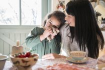 Girl being comforted by mother at dinner table — Stock Photo