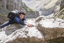 Bergsteiger klettert in unwegsamem Gelände über Felsen — Stockfoto