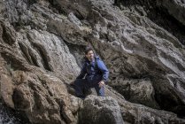 Bergsteiger sitzt in unwegsamem Gelände über Felsen — Stockfoto