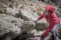 Alpiniste grimpant sur des rochers en terrain accidenté — Photo de stock