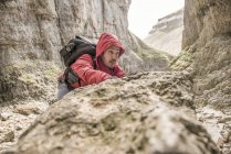 Alpiniste grimpant sur des rochers en terrain accidenté — Photo de stock