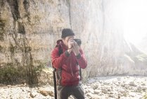 Montañista escalando rocas y tomando fotografías - foto de stock