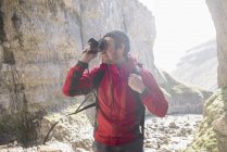 Montañista escalando rocas y tomando fotografías - foto de stock