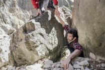 Montañistas ayudándose unos a otros durante una dura escalada - foto de stock