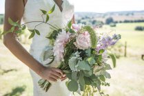 Sposa che tiene mazzo di fiori — Foto stock