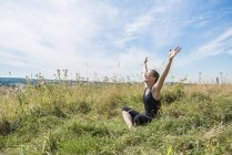 Mujer en prado practicando yoga - foto de stock