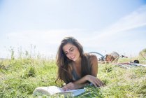 Femme lecture livre tandis que assis dans prairie — Photo de stock