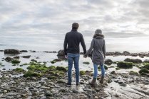 Couple marche tenant la main à travers la plage — Photo de stock