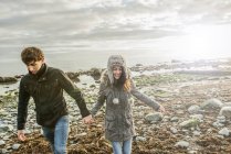 Pareja cogida de la mano en la playa - foto de stock