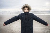 Хлопчик стоїть на пляжі з простягнутими руками — стокове фото