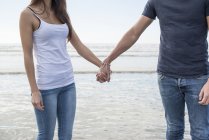 Пара стоїть на пляжі і тримає руки — стокове фото