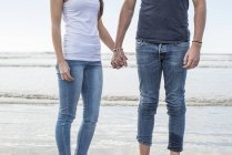 Paar steht am Strand und hält Händchen — Stockfoto