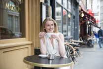 Femme assise devant le café — Photo de stock