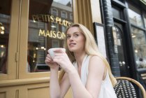 Женщина, сидящая снаружи кафе — стоковое фото