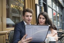 Casal olhando para menu fora do café — Fotografia de Stock