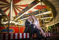Couple cuddling by carousel — Stock Photo