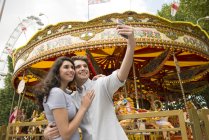 Couple taking selfie in front of carousel — Stock Photo