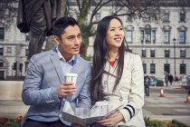 Couple sitting on parapet and drinking coffee — Stock Photo
