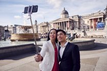 Coppia prendere selfie contro fontana a piazza trafalgar — Foto stock