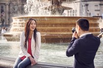 Uomo fotografare fidanzata vicino fontana — Foto stock