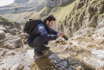 Alpinista riempiendo la sua bottiglia d'acqua — Foto stock