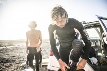 Men in wet suits preparing to go surfing — Stock Photo