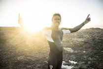 Surfista en traje de neopreno levanta brazos - foto de stock