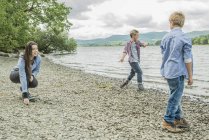 Femme et deux garçons jouant sur la rive — Photo de stock