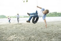 Donna e due ragazzi giocare su pneumatico — Foto stock