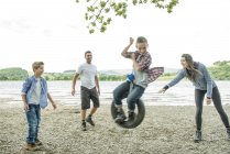 Family playing on tire hanging from tree — Stock Photo