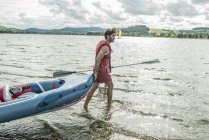 Hombre arrastrando un kayak en el agua - foto de stock