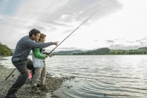 Padre e hijo pescando desde la orilla - foto de stock