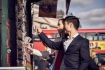 Casal escolhendo cartões postais enquanto em pé na rua . — Fotografia de Stock