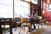 Женщина сидит за столом и использует смартфон — стоковое фото