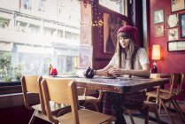 Mujer sentada en la mesa en la cafetería - foto de stock