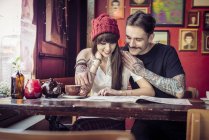 Paar schaut sich Speisekarte im Café an — Stockfoto