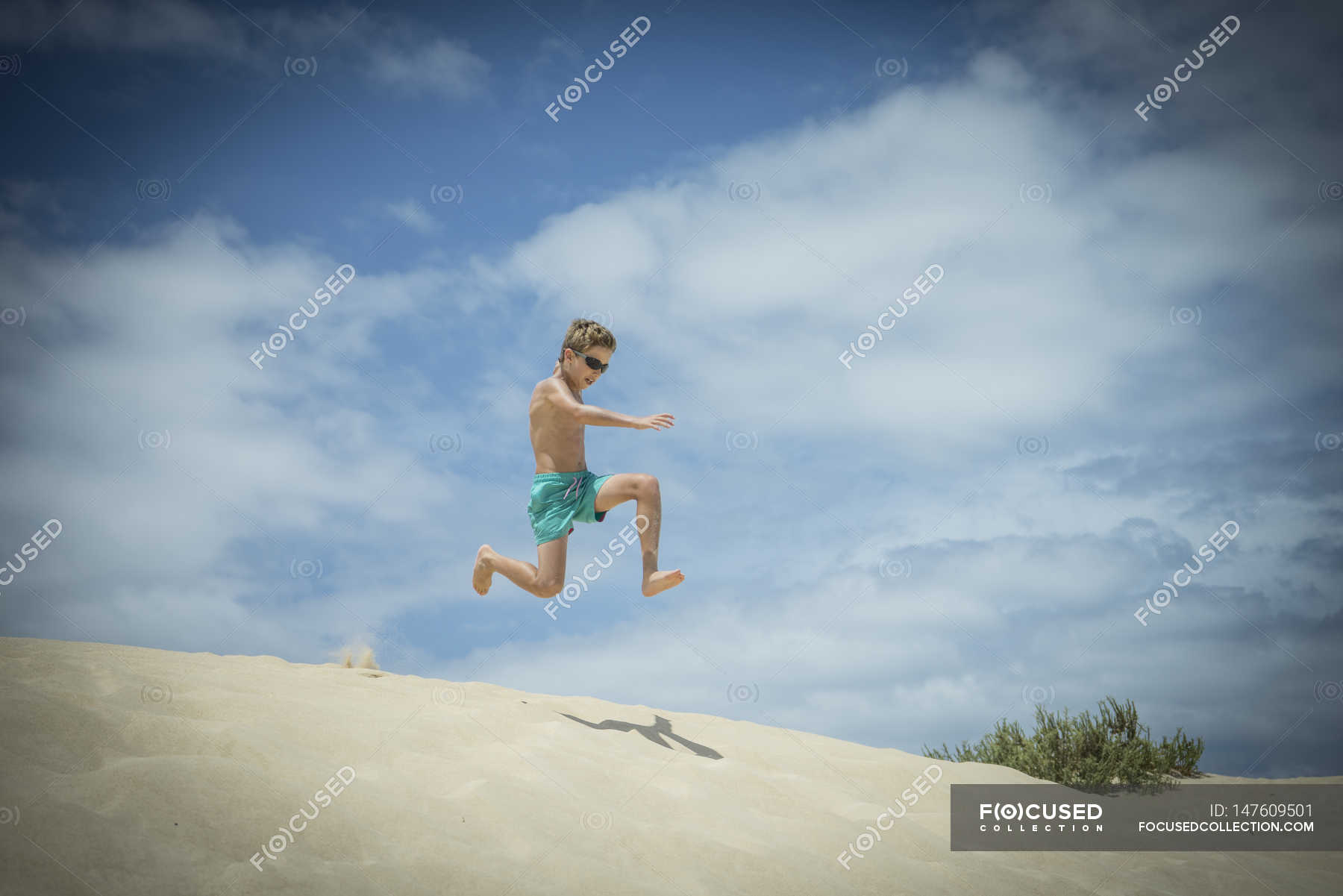 Boy jumping in sand dunes at beach — corralejo, daylight Stock Photo