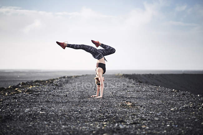Woman doing handstand on deserted road — Stock Photo