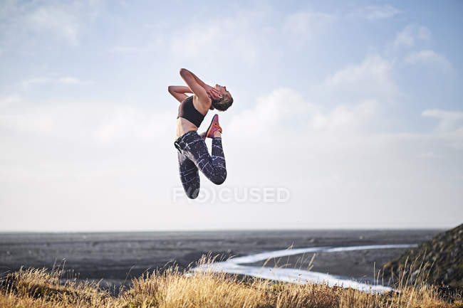 Woman leaping by deserted unmade road — Stock Photo