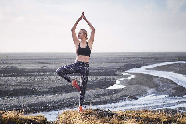 Woman practicing yoga by deserted road — Stock Photo