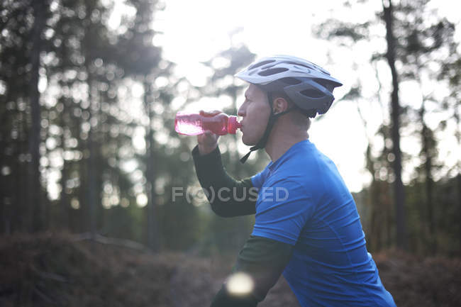 Людина п'є воду в той час як гірський велосипед — стокове фото