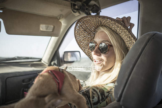 Femme surfeuse assise en voiture avec chien — Photo de stock
