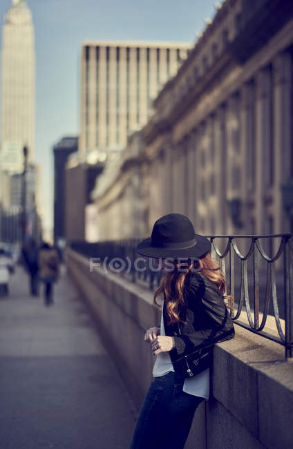 Donna in jeans e cappello in attesa contro ringhiere — Foto stock